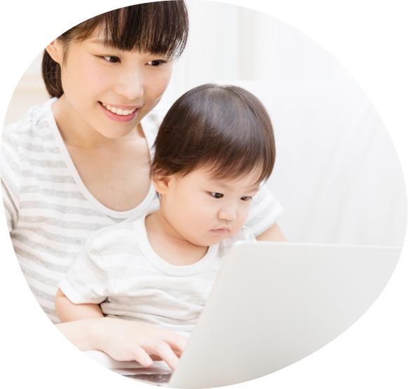 パソコンに向かうママとママの膝に座る子どもの写真